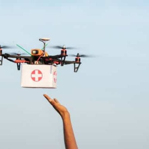 Hands receiving medical aid kit or medicines from drone or quadcopter during covid-19 or coronavirus lockdown - Medical Industry Logistics for Drug Transport concept during lockdown